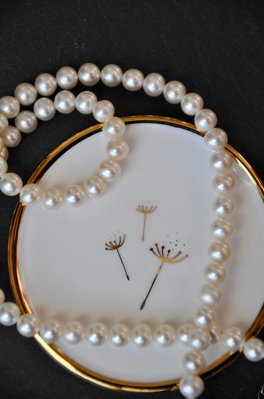 Gold dandelion trinket dish holding a necklace