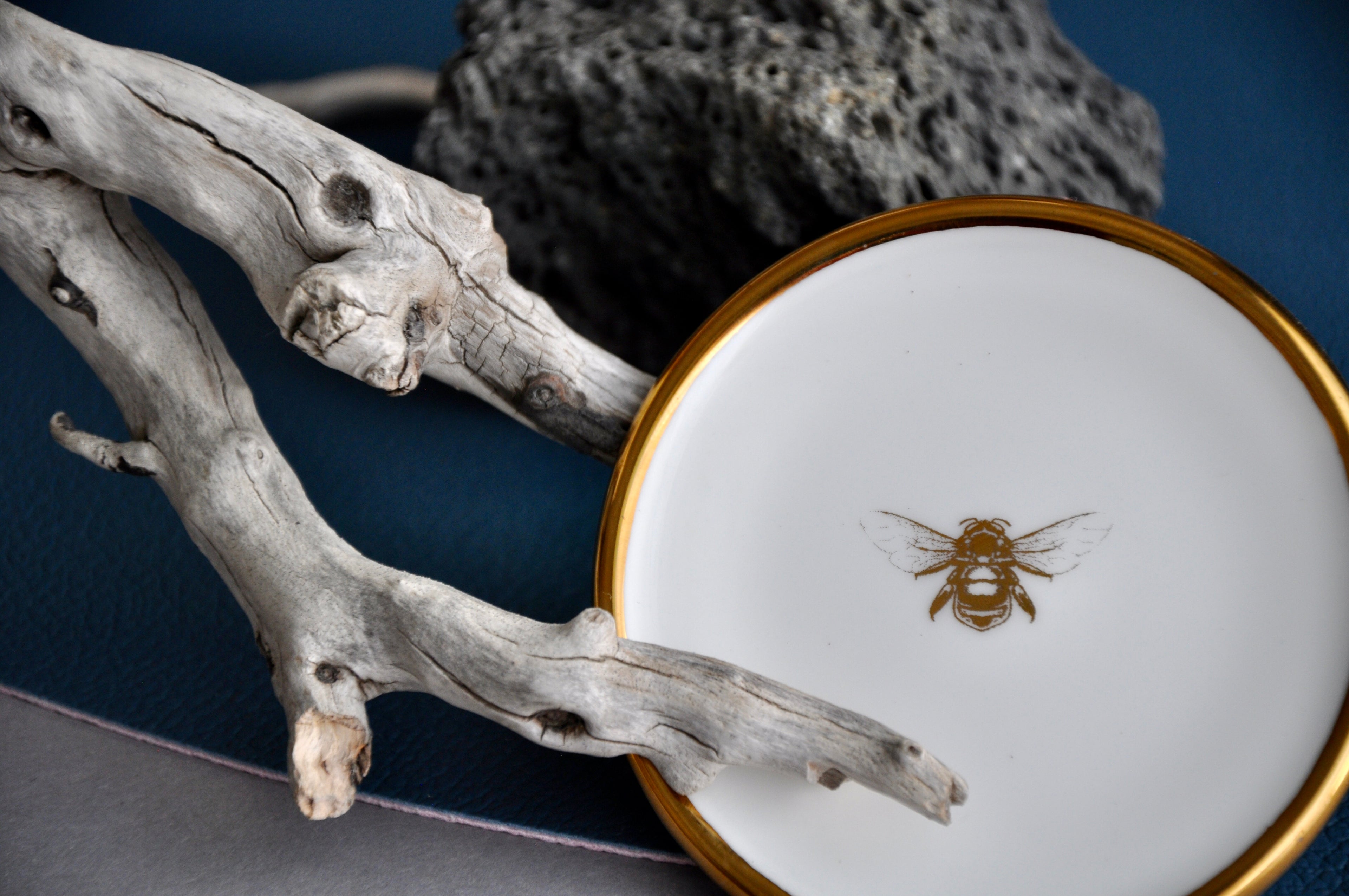 Fine bone china designer trinket dish featuring a golden bee motif and gold rim, ideal for gift ideas, premium gifts, homeware, and jewellery trays. This elegant piece makes a perfect small luxury gift, combining style and functionality. Ideal for adding a touch of sophistication to any home decor or as a thoughtful present for special occasions. Perfect for those who appreciate fine craftsmanship and unique design in their home accessories and gift selections.
