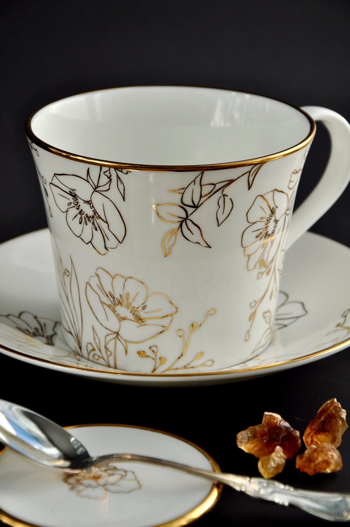 Blossom porcelain trinket dish serving as a teaspoon rest next to a matching tea cup and saucer