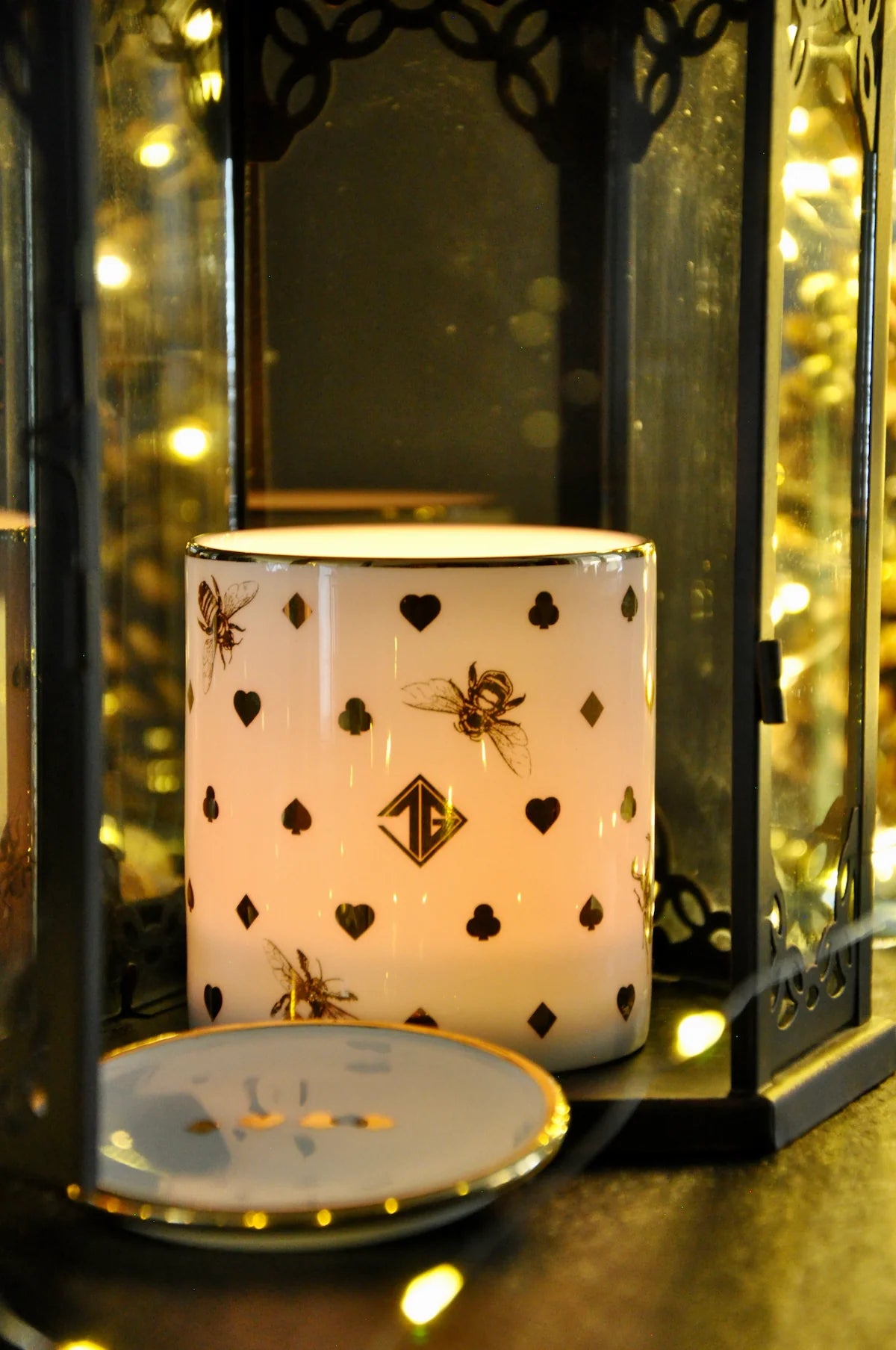 Lit candle glowing through translucent fine bone china, placed beside a matching  trinket dish.
